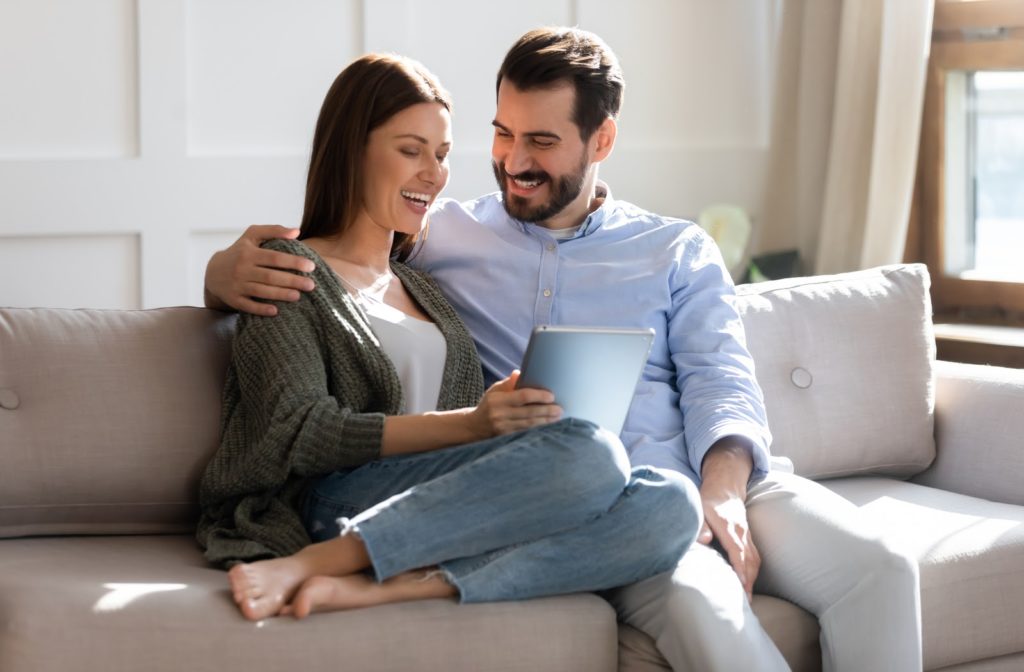 Relieved couple sitting on the couch reading an email telling them they've been approved for a payday advance. 