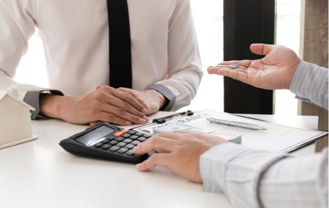 Loan lender talking to client that has bad credit about loan deal with calculator and paper on table