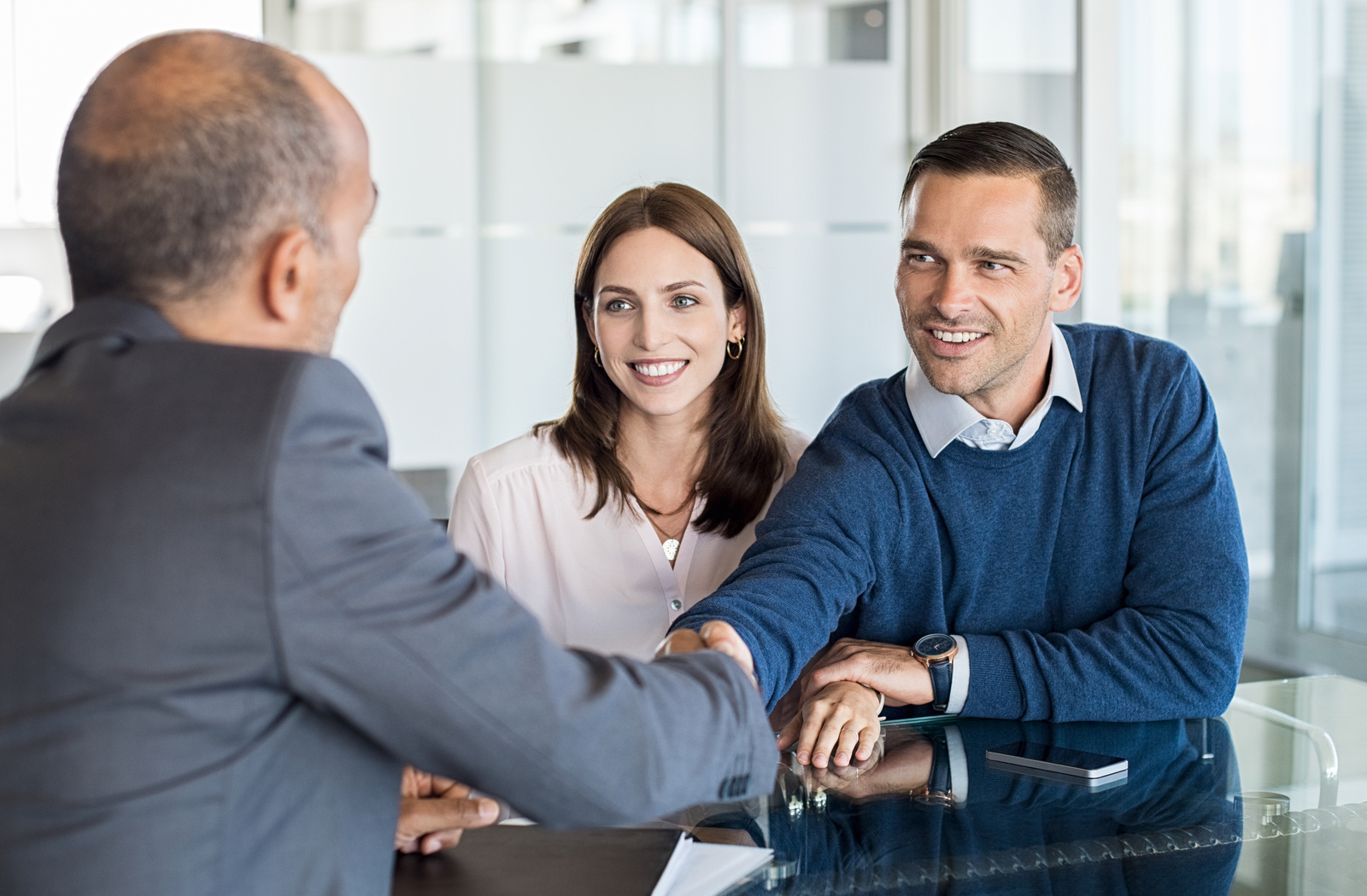 Couple shaking hands with professional after refinancing personal loan