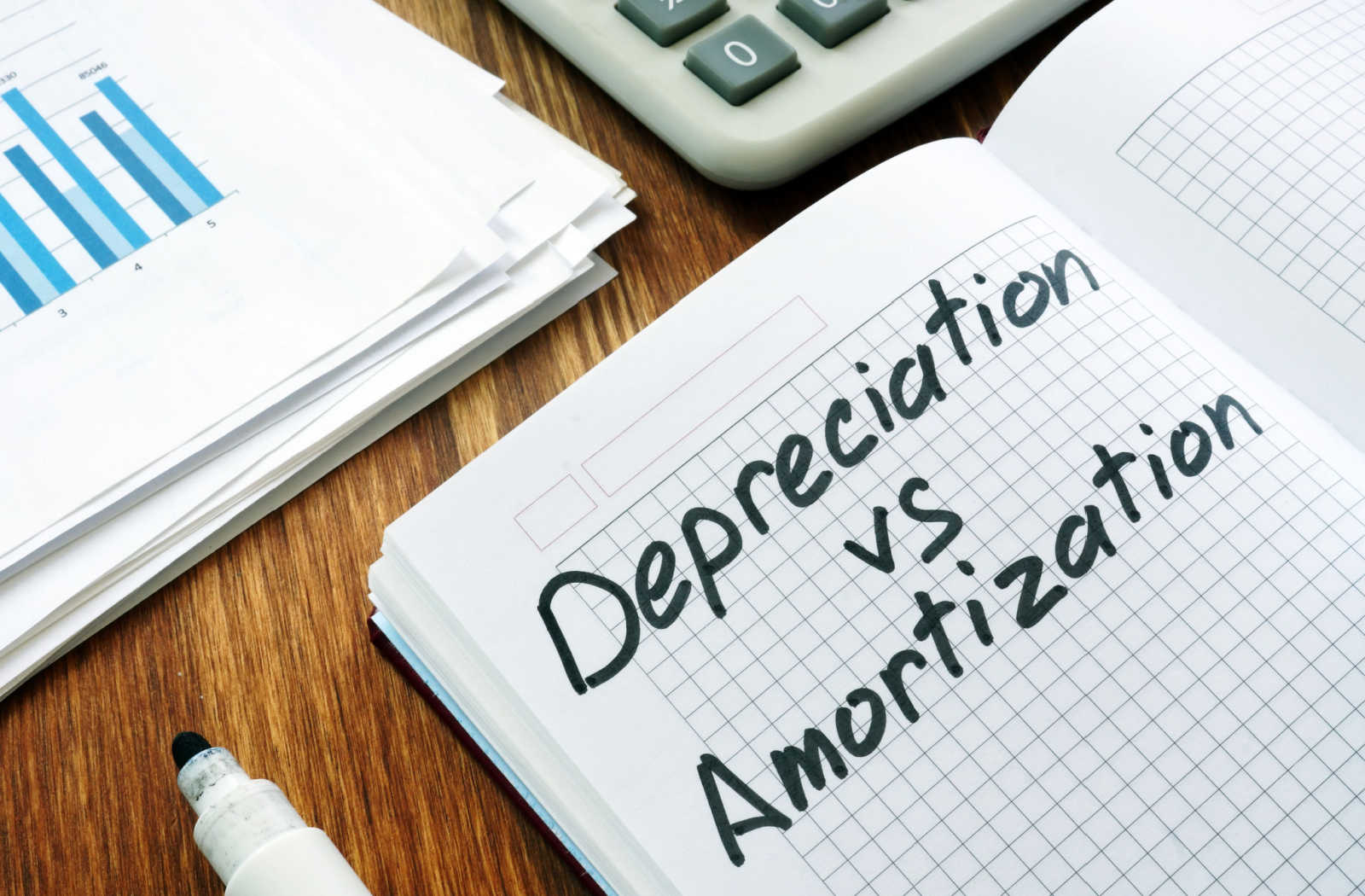 An open notebook with the words "depreciation vs. amortization" written on the page.