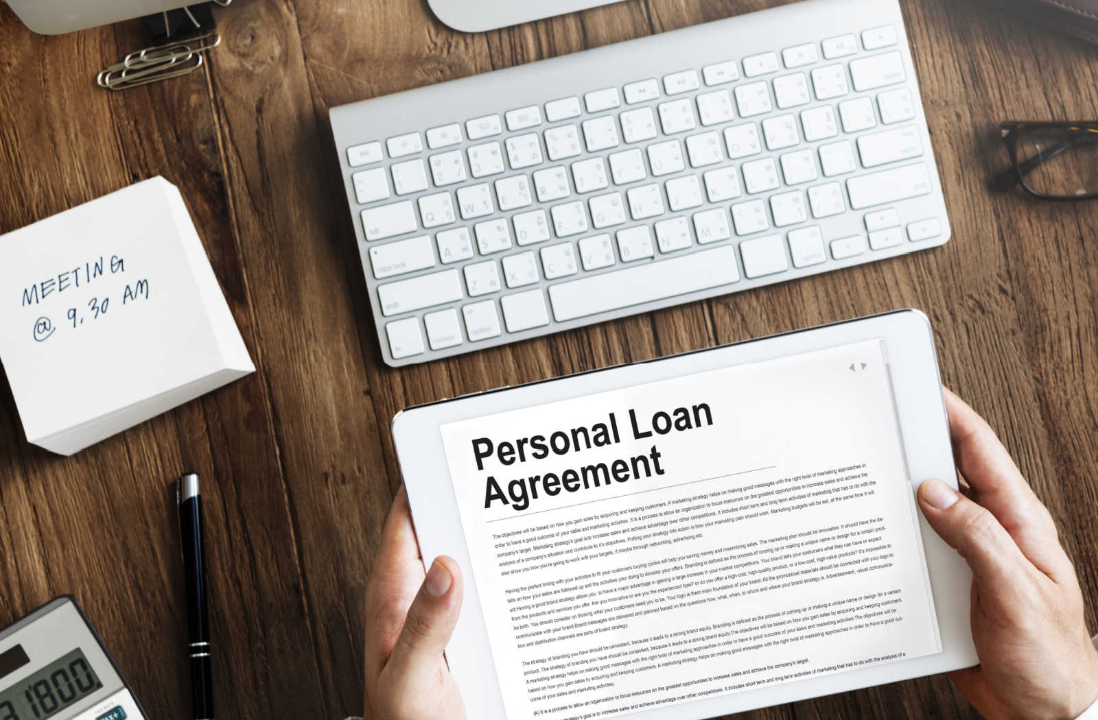 A male hand is holding an Ipad and on the Ipad screen is a written personal loan agreement.