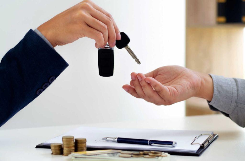 A financial advisor from handing over the car keys to a client after the car loan is approved and papers are signed.