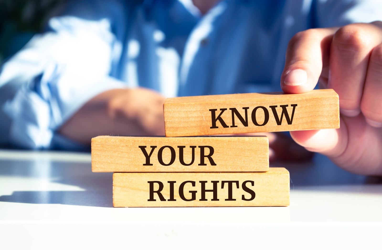 A male in a blue shirt places blocks on a table that read "Know your rights."