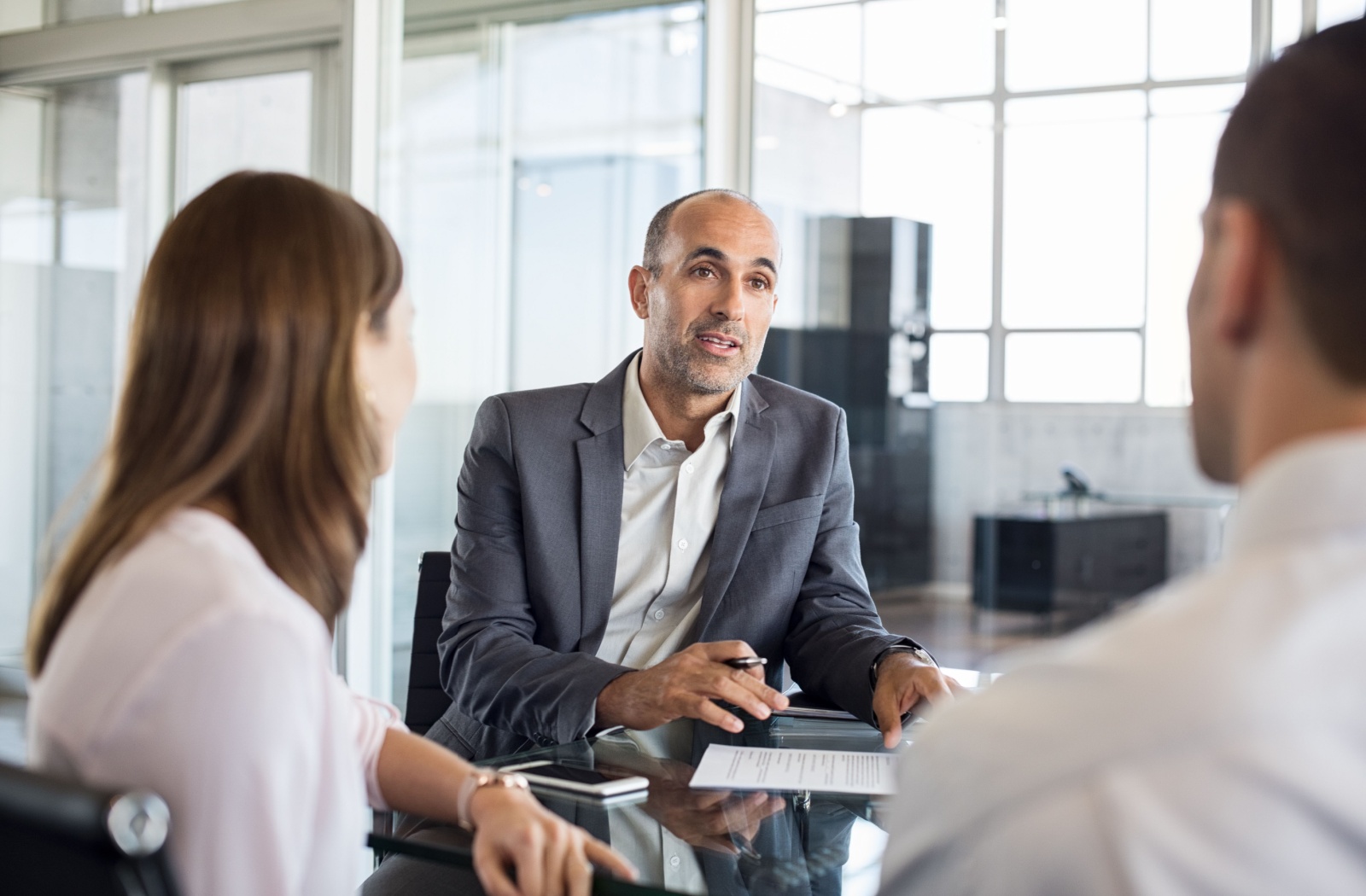 2 people meeting with a lender in a brightly lit office to discuss the eligibility requirements for no credit check loans.