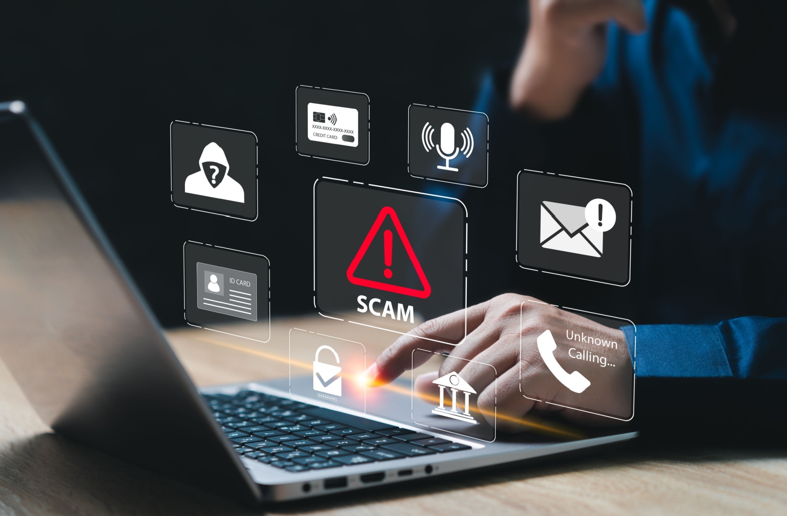 A holograph illustrating different online scams overtop a person working on a laptop.