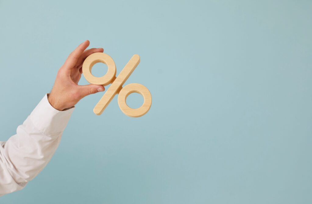 A hand holding up a wooden percent symbol.